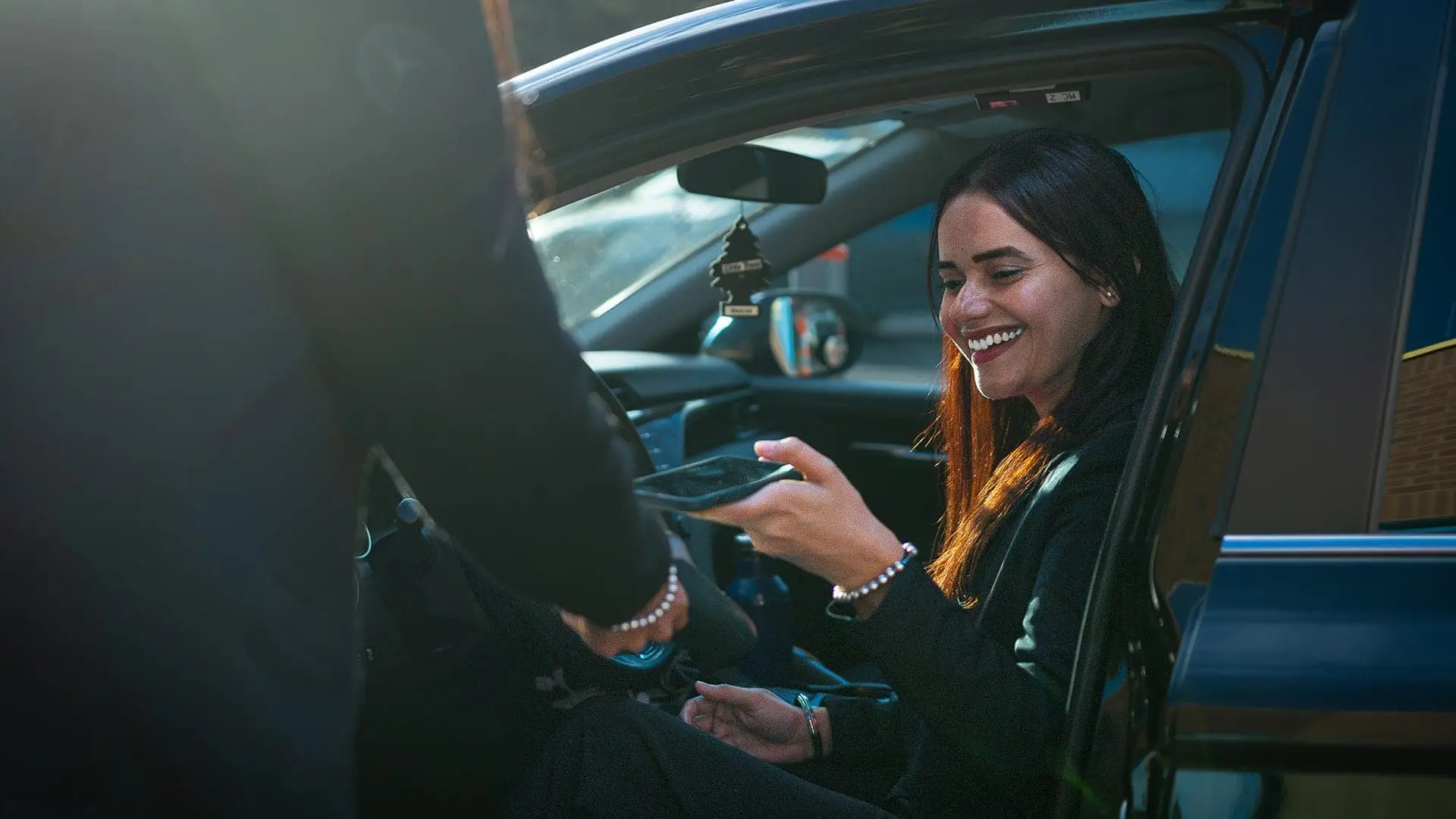 Happy customer paying using her phone from her car.