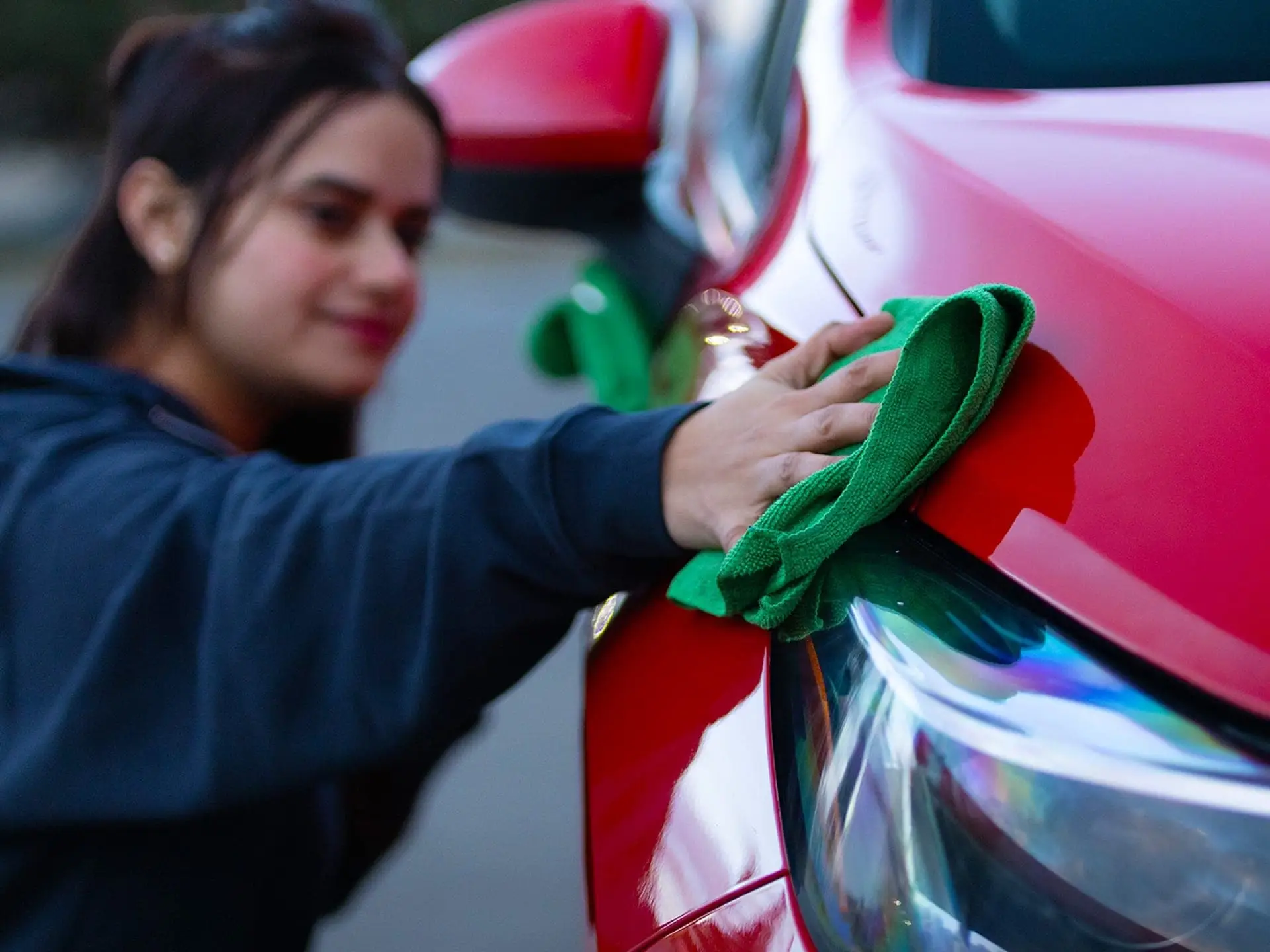 Valet technician detailing a customer's red car