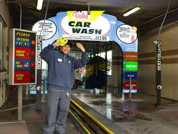 Valet technician signaling customer inside the exterior car wash bay