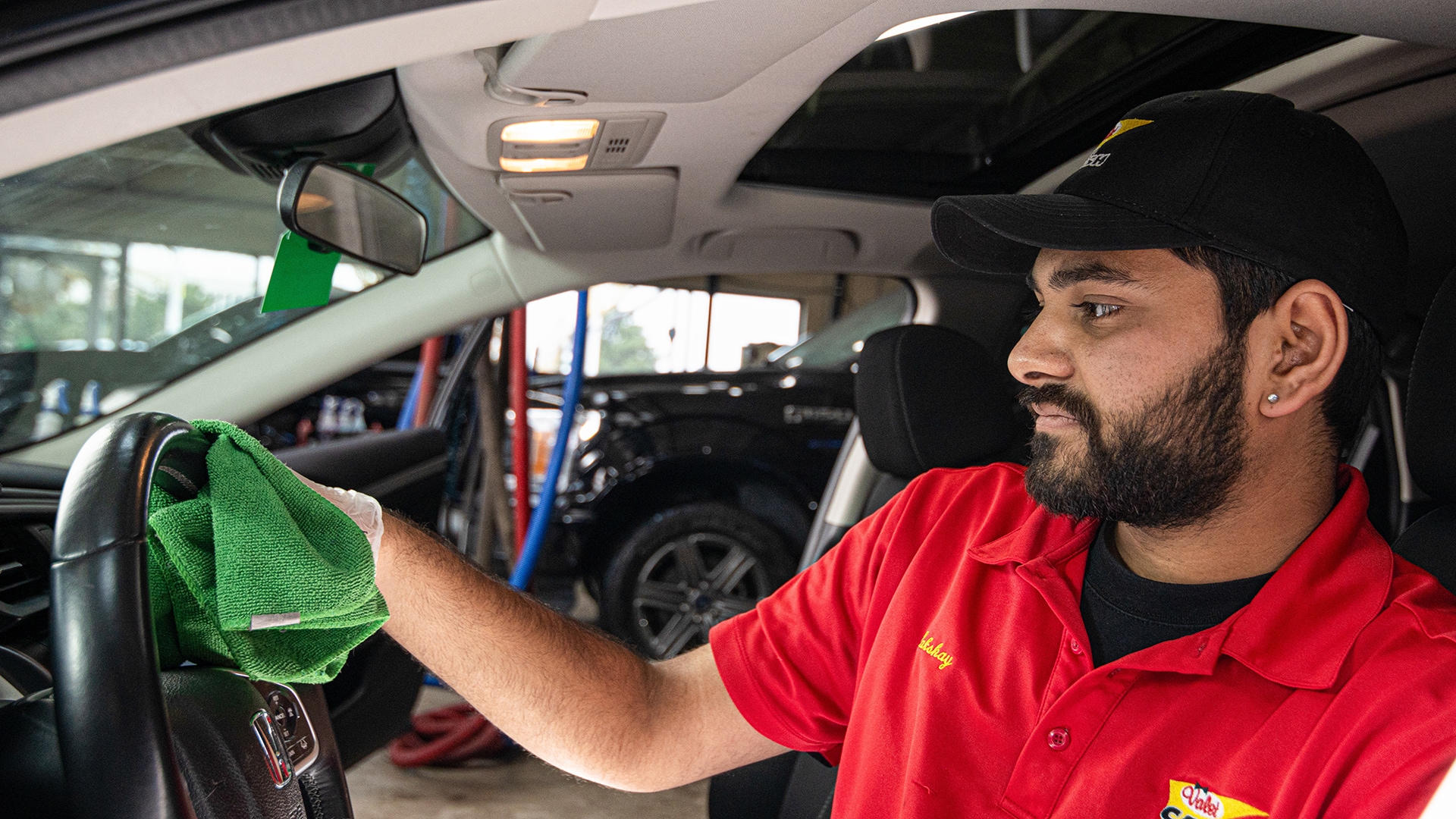 Valet technician cleaning a customer's car steering wheel