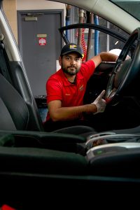 Valet technician dilligently taking care of every nook and cranny of a customer's car interior