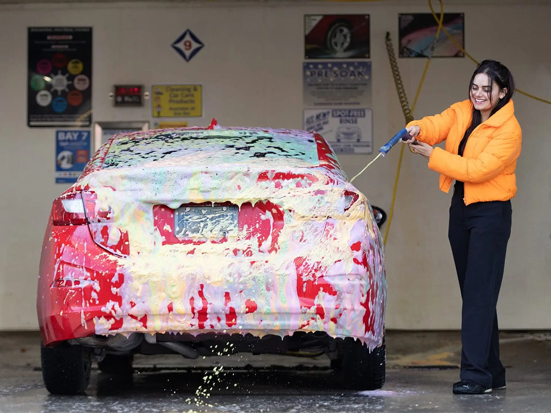 Happy customer applying foam to their red car