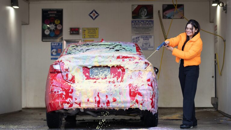 Happy customer applying foam to their red car
