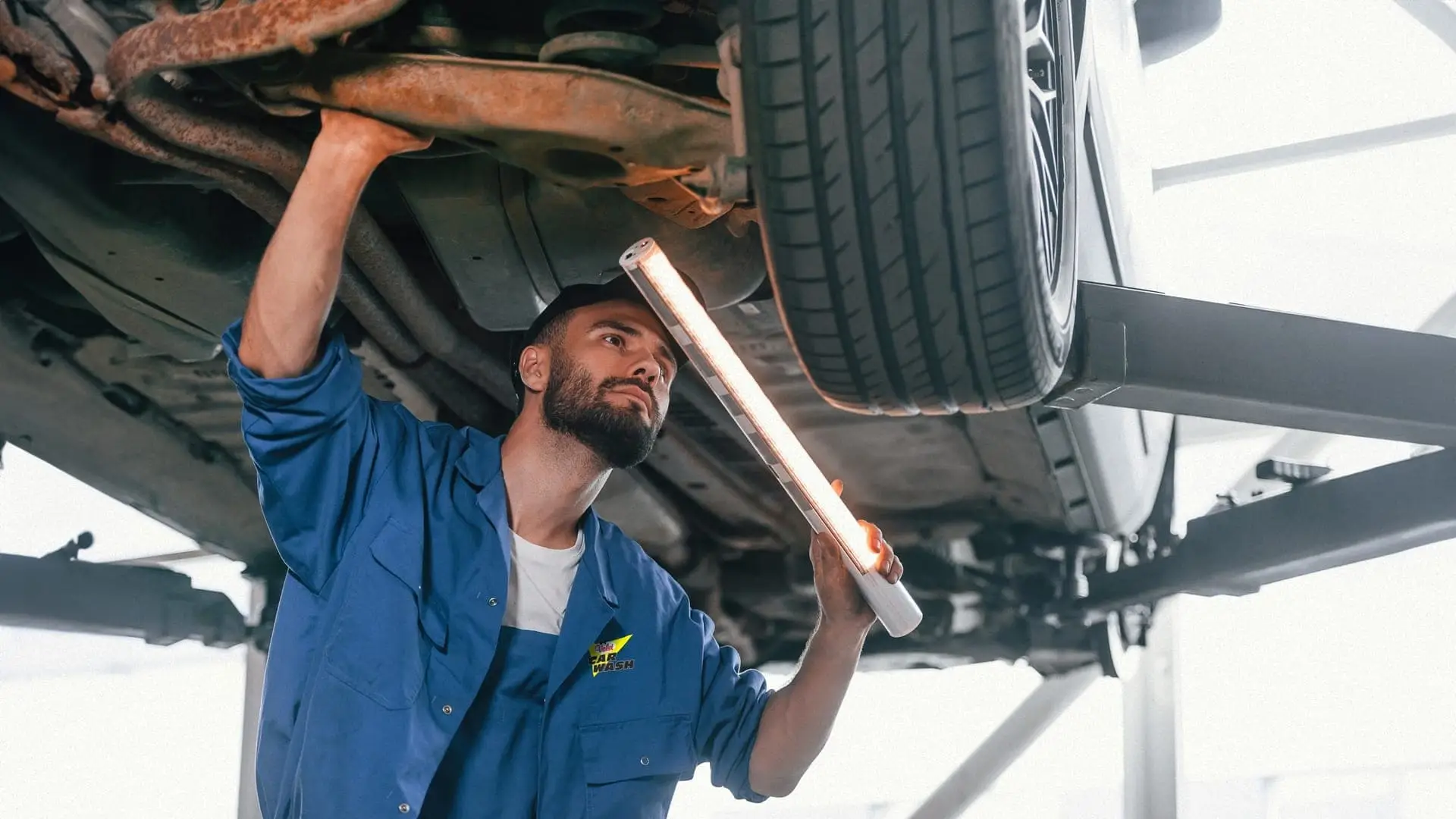 Valet technician checking car underside for rust