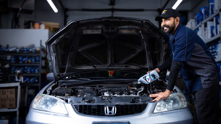 Valet technician patiently adding fresh oil to the engine of a customer's car