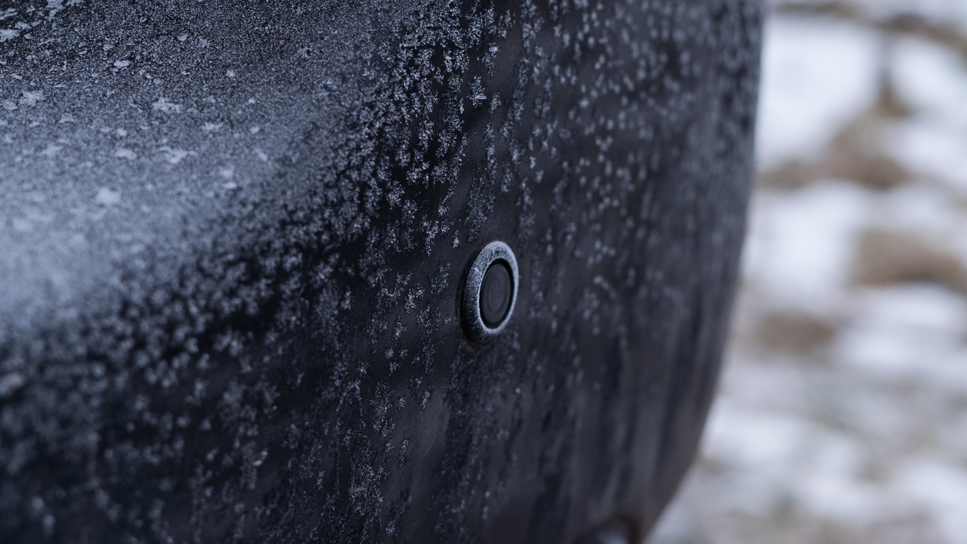 Picture of a car front parking sensor on a frozen bumper