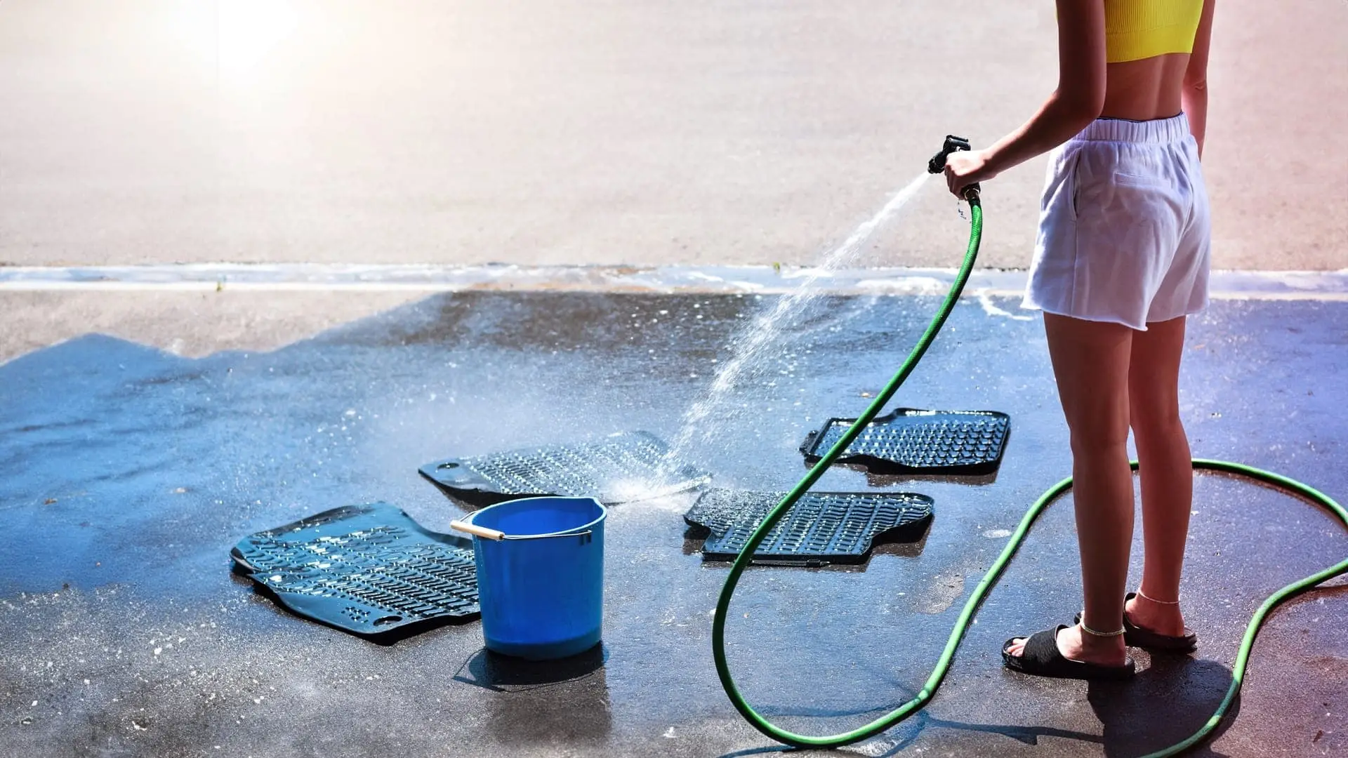 Person pressure washing their car mats in their driveway