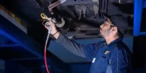 Valet technician applying No Drip Oil Spray Rust Protection to the underside of a vehicle, ensuring long-lasting protection against rust and corrosion in harsh conditions.