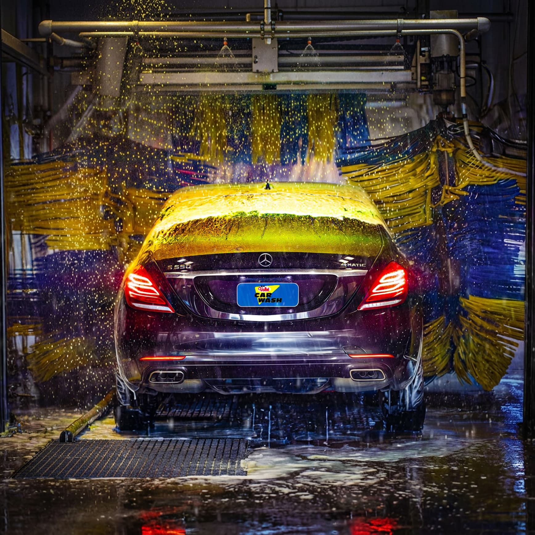 Sedan driving through Valet Car Wash automated tunnel with foam wash curtains and high-pressure water spray